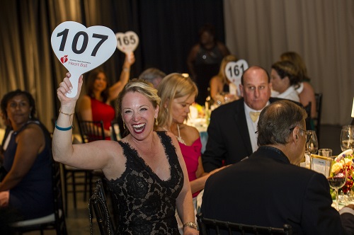 Woman in ballroom holding up her bidder paddle